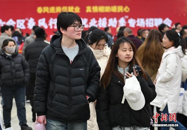 应聘者在招聘摊位前查看招聘信息。图片来源：中新社泱波