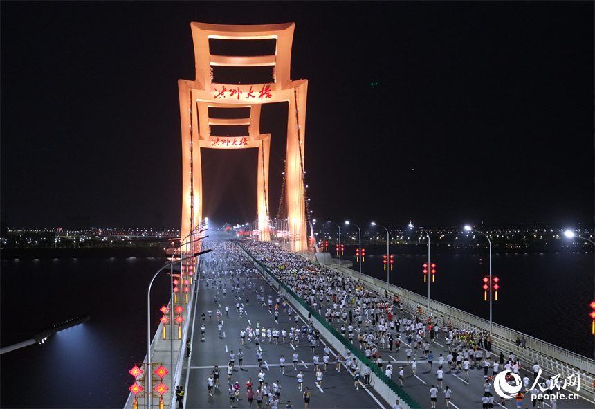 2026南昌万人夜跑活动30日晚鸣笛开跑。图为跑友奔跑在洪州大桥上。时雨摄